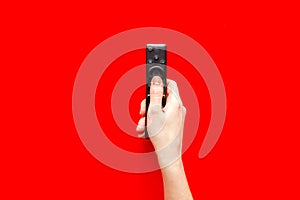 Watch TV concept. TV remote in hand on red background top-down copy space