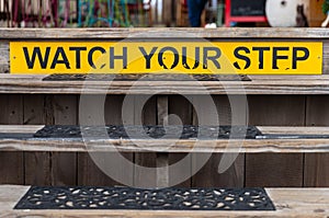 Watch your Step sign on a wooden set of stairs