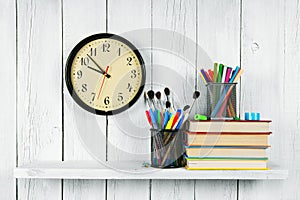 Watches, books and school tools on wooden shelf.