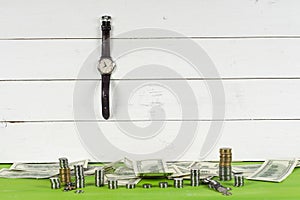 Watches, coins and dollars on wooden table on bright background.