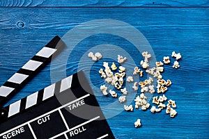 Watching the film. Movie clapperboard and popcorn on blue wooden table background top view copyspace