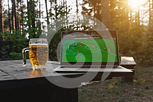 Watching a football match on a laptop outdoors in the forest