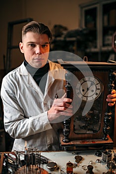 Watchmaker adjusts the mechanism of old wall clock