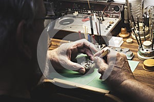 Watchmaker at his workbench full of tools where he repairs a clock machine