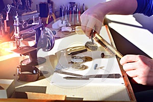 Watchmaker repairs watch in workshop. Workplace of watch repairer. Process of repair mechanical watches.