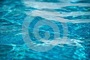 Water background, ripple waves. Blue swiming pool pattern. Sea surface. Water in swimming pool with sun reflection