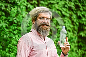 Water balance. Man bearded tourist drinking water plastic bottle nature background. Summer heat. Thirsty guy drinking