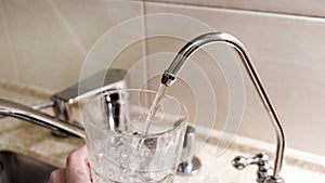 Water being poured into glass from kitchen tap. Concept. Close-up of tap water being poured into a glass in the kitchen