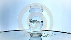 Water being poured into tall glass in slow motion isolated white background