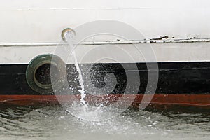Water being pumped out the side of a small boat