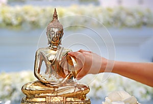 Water blessing ceremony for Songkran Festival or Thai New Year. People paying respects to a statue of Buddha by pouring water onto