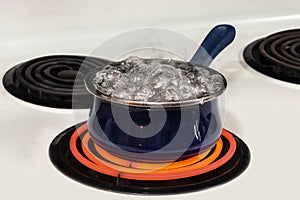 Water Boiling Out of Blue Pot On Stove With Copy Space