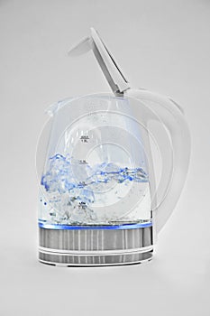 Water boils in a transparent open electric kettle on a white background. macro.