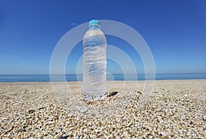 Water bottle frozen cold on the sand of the beach in a hot summer day