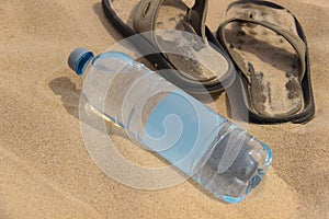 Water bottle mockup. Half-liter plastic water bottle lies on the sand. Beach vacation kit