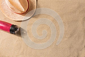 Water bottle and straw hat on sand