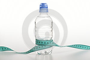 Water bottle tied with cyan measure tape on white background