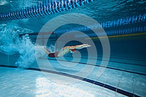 Water bubbles demonstrating speed. Young man, swimming athlete in motion in pool training, preparing for competition
