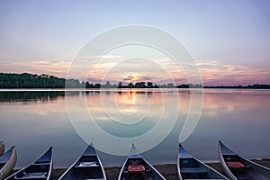 the water is calm with several boats docked on it and the sun setting over the