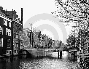 Water canal, aka gracht, and narrow houses along it in Amsterdam city centre, Netherlands, black and white image photo