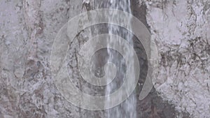 Water cascade pouring over rocky cliff in mountains