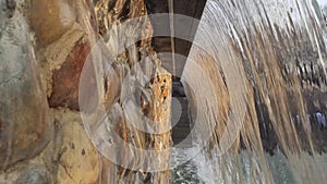 Water cascade running in city park with stone wall