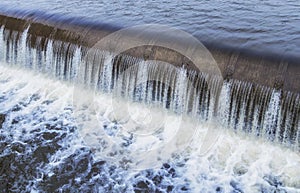 Water cascade streaming down a lasher of dam, water saving concept