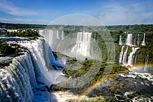 Water cascading over the Iguacu falls with rainbow in foreground