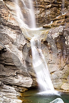 Water cascading over rocks, waterfall and autumn colors in the mountains, yellow and red trees