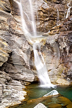 Water cascading over rocks, waterfall and autumn colors in the mountains, yellow and red trees