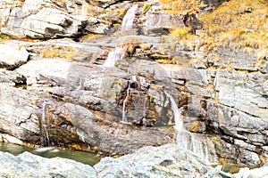 Water cascading over rocks, waterfall and autumn colors in the mountains, yellow and red trees