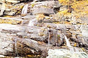 Water cascading over rocks, waterfall and autumn colors in the mountains, yellow and red trees