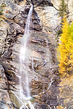 Water cascading over rocks, waterfall and autumn colors in the mountains, yellow and red trees
