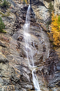 Water cascading over rocks, waterfall and autumn colors in the mountains, yellow and red trees