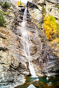 Water cascading over rocks, waterfall and autumn colors in the mountains, yellow and red trees