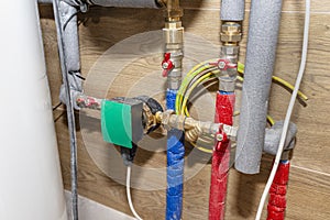 Water circulation pump for underfloor heating in a modern gas boiler room lined with ceramic tiles.