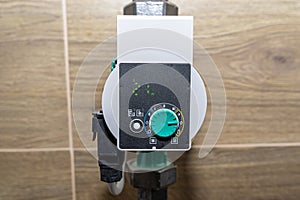 Water circulation pump for underfloor heating in a modern gas boiler room lined with ceramic tiles, shows a value of 21 watts.