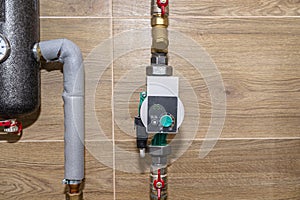 Water circulation pump for underfloor heating in a modern gas boiler room lined with ceramic tiles, shows a value of 25 watts.