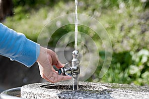 A hand holding a public drinking fountain. Water coming out splashing upward.