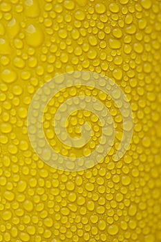 Water condensate drops on a surface of yellow color, close up
