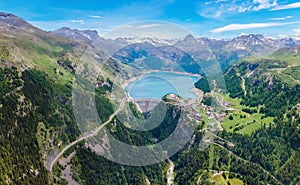 Water dam and blue reservoir lake aerial overview in Alps mountains in summer generating hydroelectricity. Low CO2 footprint,