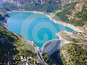 Water dam and blue reservoir lake aerial view in Alps mountains generating hydroelectricity. Low CO2 footprint, decarbonize,