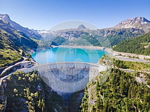 Water dam and reservoir lake aerial view in Alps mountains in summer generating hydroelectricity. Low CO2 footprint, decarbonize,