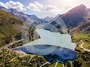 Water dam and reservoir lake in Swiss Alps generating hydroelectricity. Aerial view of arch dam between mountains. Hydropower