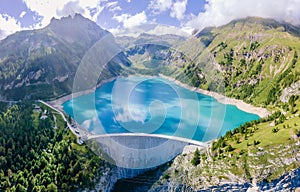 Water dam and reservoir lake in Swiss Alps mountains producing sustainable hydropower, hydroelectricity generation, renewable