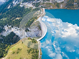 Water dam and reservoir lake in Swiss Alps to produce hydropower, hydroelectricity generation, renewable energy, aerial drone