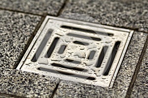 Water drain vent in kitchen, bathroom or basement ceramic tiled old vintage floor. Geometric abstract beige background