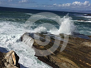 Water draining from rock and wave crashing over it in Montana De Oro California photo