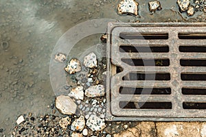 Water drains from the drain hatch. Drainage fountain of sewage. Accident in the sewage system. Dirty sewage flows on the road.