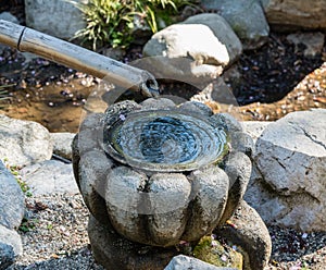 Water dripping through a bamboo pipe into an ornamental stone pot